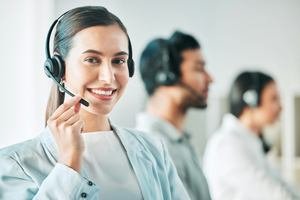 Portrait of a young call centre agent working in an office with her colleagues in the background